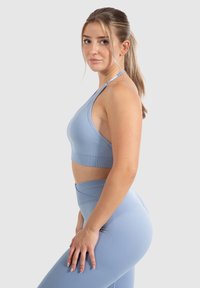 Lichtblauw sportcrop top met dunne bandjes en geribbelde textuur, gecombineerd met bijpassende high-waisted leggings in een vergelijkbare tint.