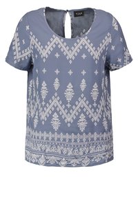 Modrá blůza s krátkým rukávem, zdobená bílými geometrickými vzory, kulatým výstřihem a výřezem na zádech, v uvolněném střihu. Hladká textura látky.