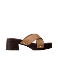 Sandale en daim beige avec brides croisées, clous dorés et plateforme à talon moyen épaisse brun foncé.