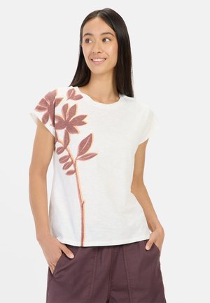 Witte T-shirt met korte mouwen en een bloemenprint in roest en beige aan de linkerkant. Zachte textuur, ontspannen pasvorm en ronde halslijn.