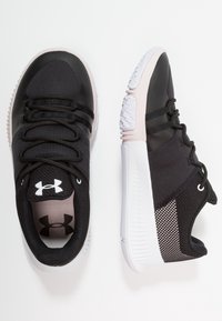 Scarpe da ginnastica Under Armour in bianco e nero con lacci neri, tessuto in rete e suole bianche imbottite, mostrate da viste superiori e laterali.