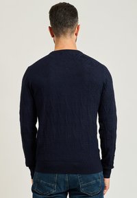 Maglione a maglia blu navy con un motivo geometrico testurizzato e polsini a coste, dotato di scollatura rotonda e design aderente.