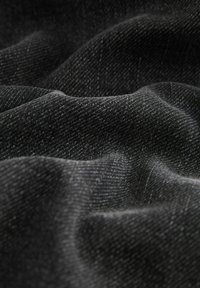 Țesătură din denim neagră cu o țesătură texturată, arătând un luciu subtil și pliuri fine, indicând moliciune și flexibilitate. Fără modele distincte vizibile.