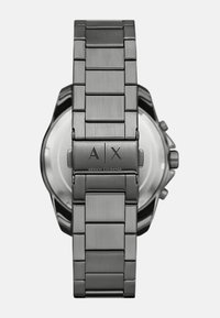 Nerūdijančio plieno laikrodis su šlifuotu paviršiumi, sidabrinės spalvos, su sagtimi, ant kurios išgraviruotas logotipas "A|X" - Armani Exchange.