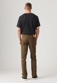 Dark gray T-shirt paired with olive green pants featuring a rear patch label, five-pocket design, and straight leg cut.