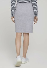 Jupe crayon en coton gris, design ajusté, long jusqu'aux genoux. Associée avec des baskets blanches. Rayures horizontales sur le haut à manches longues.