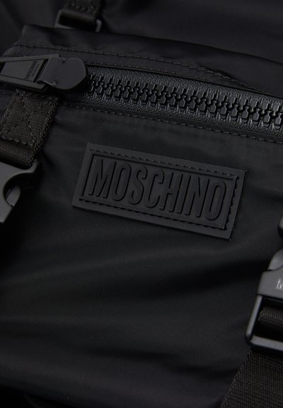 Rucsac din nylon negru cu finisaj texturat, un logo MOSCHINO din cauciuc proeminent și accesorii din metal negru cu închidere cu fermoar.