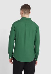 Groene lange mouwen overhemd met een klassieke kraag, knoopmanchetten en een rugplooi voor verbeterde bewegingsvrijheid. Gladde stof met een matte afwerking.