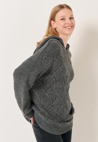 Maglione grigio lavorato a maglia con un motivo a onda testurizzato, vestibilità ampia e scollatura larga. Polsini e orlo a coste, dall'aspetto accogliente.