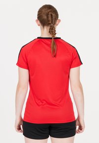 Rød sports T-shirt med sorte detaljer, korte ærmer og rund hals. Stoffet ser glat og let ud, designet til sportstøj.