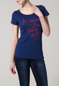 Marinblå bomulls-t-shirt med rund halsringning, korta ärmar och röd grafisk text med detaljerna "Hilfiger Denim Young Hearts".
