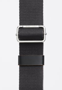 Czarny pas z tkaniny o splocie, z błyszczącą srebrną prostokątną klamrą i czarnym skórzanym akcentem. Materiał o fakturze z diagonalnym wzorem.