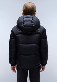 Czarna kurtka puchowa z dużym kapturem, z pikowanymi sekcjami i błyszczącym wykończeniem. Logo nadrukowane z tyłu. Elastyczne mankiety.