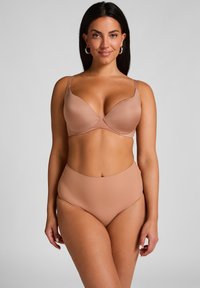 Beiges Lingerie-Set mit einem bh mit formenden Cups, verstellbaren Trägern und hohem Taillenbrief, beide aus glattem, dehnbarem Material.
