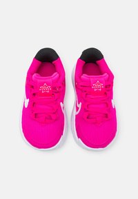 Scarpe da ginnastica di un vivace rosa brillante con una texture rigata, accenti bianchi, punta tonda e collarino nero. Presentano un logo "Star Runner" sulla linguetta.