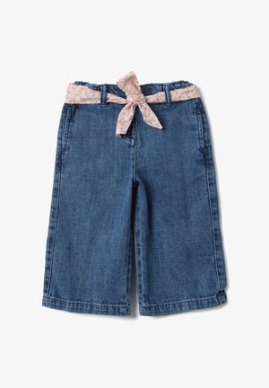 Pantaloni ampi in denim blu con cintura di tessuto floreale rosa annodata a fiocco in vita, vista dall'alto su sfondo bianco.