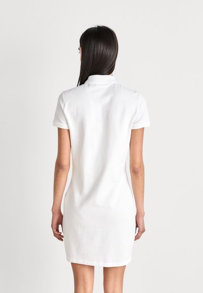 Robe polo en coton blanche à manches courtes et col classique, avec une coupe droite et un design longueur genou.