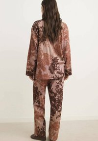 Conjunto de loungewear en tonos marrón y rosa con un ajuste relajado, que incluye mangas largas y pantalones anchos, hecho de una suave tela texturada.