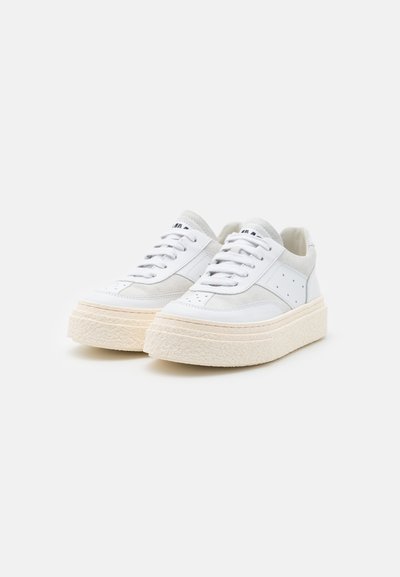 Hvite sneakers med en teksturert plattformsåle, lær-overdel, snøredesign og subtile grå detaljer på sidene og tungen.