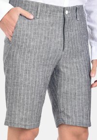 Shorts in lino grigio con strisce verticali bianche, dotati di chiusura a bottone e zip, due tasche laterali e una vestibilità sartoriale.