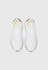 Sneaker sportive bianche con una tomaia in tessuto liscio, chiusura con lacci, dettagli neri sul tallone e suola in gomma testurizzata.