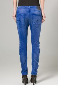 Blå skinny jeans med en jämn textur, med två bakfickor med snedställda lock och en smal passform.