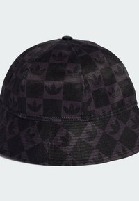 Chapeau de seau noir en tissu texturé, arborant un motif à damier et un design de logo répété dans des tons sombres.
