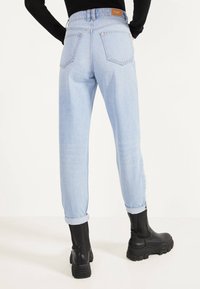 Ljusblå denimjeans med en avsmalnande passform, uppvikta fållar och två bakfickor. Kombinerad med svarta ankelstövlar med tjock sula.