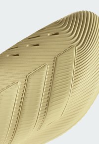 Talpă galbenă de încălțăminte sport cu textură nervurată, dungi diagonale ridicate și orificii de ventilație pentru o aderență și flexibilitate sporită.