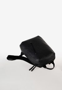 Zaino nero realizzato in pelle liscia, con forma rettangolare, tasca frontale con zip e spallacci regolabili. Design minimalista.