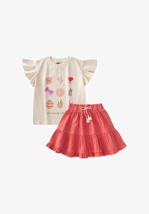 Top crema de manga corta con estampados florales y círculos a rayas combinado con una falda coral con volantes, que cuenta con cintura con cordón y borlas.