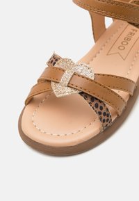Tan syntetiska sandaler med en leopardtryckt rem och en glittrande hjärtformad detalj. Slät innersula med stickad detalj och en brun sula.