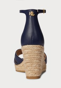 Navy kék wedge szandál textúrált juta sarkal, sima bőrszíjjal és arany logóval a hátsó részen.