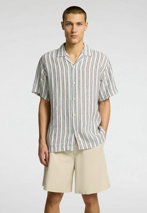 Camicia a maniche corte, con bottoni e strisce verticali in tonalità neutre. Realizzata in tessuto leggero, dalla vestibilità comoda. Abbinata a pantaloni corti beige.