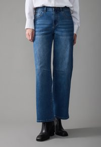 Blue wide-leg jeans made of denim with a faded finish, featuring classic five-pocket design and subtle stitching details.