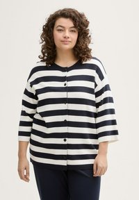 Marineblau und weiße gestreifte Strickjacke mit Dreiviertelärmeln und schwarzen Knöpfen, die einen lockeren Schnitt und einen weichen, strukturierten Stoff aufweist.