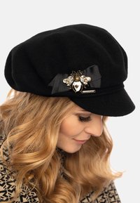 Zwarte wollen newsboy pet met een decoratieve bij broche, voorzien van een zwarte lint en kristallen accenten aan de zijkant.