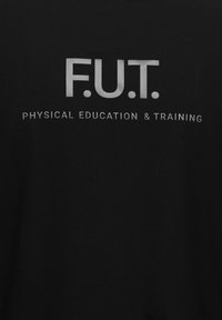 Svart t-shirt med vittryckt text: "F.U.T." ovanför "FYSISK UTVECKLING & TRÄNING." Enkel design, rund halsringning, korta ärmar.