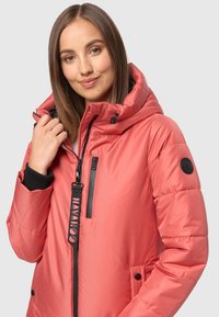 Padded koralna jakna s visokim ovratnikom, podesivom kapuljačom, zatvorenim džepovima i crnim detaljima. Ima elastične manšete i logotip.