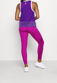 Fialový sportovní nástavec s bílým lemováním, doplněný přiléhavými růžovými legínami. Oba z elastické látky s hladkou texturou.