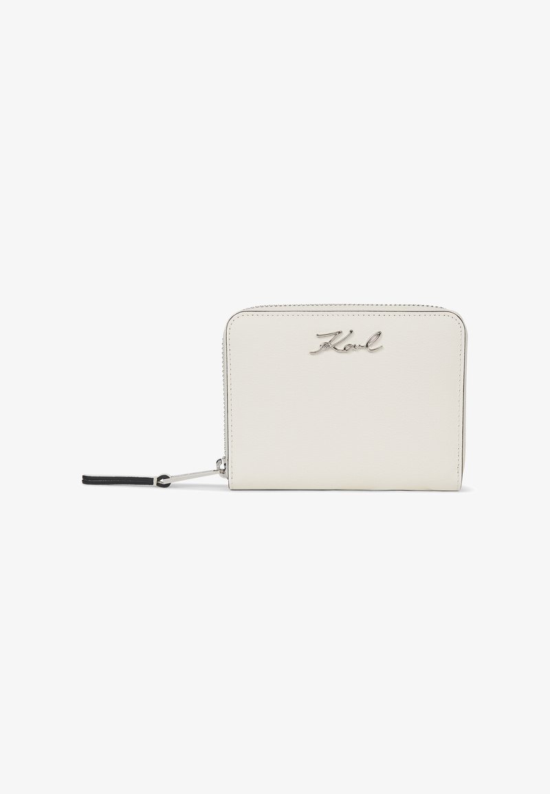 Portefeuille rectangulaire blanc zippé avec logo argenté "Karl" et languette noire sur fond blanc.