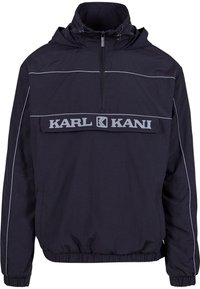 Black windbreaker jacket featuring a half-zip, kangaroo pocket, elastic cuffs, and contrasting grey piping with "KARL KANI" logo.