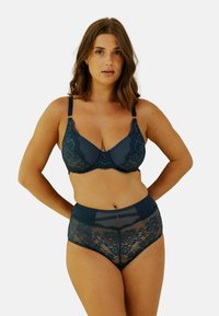Ensemble de lingerie en vert foncé comprenant un soutien-gorge avec des détails en dentelle et une culotte taille haute avec des motifs floraux et des accents en tulle.