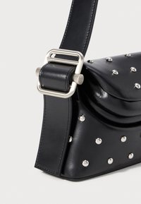 Borsa a tracolla nera in pelle con finitura testurizzata, caratterizzata da borchie argentate e una fibbia metallica sul manico. Forma sagomata, design compatto.