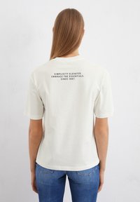 Kerman lyhythihainen t-paita, jossa on rento istuvuus. Takana teksti: "Yksinkertaisuus nostettu. Hyväksy perusasiat. Vuodesta 1967."