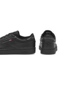 Dvoje čiernych tenisk Reebok zobrazených zboku a zozadu, so známym logom Reebok a malou vlajkou Union Jack na boku.