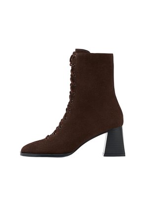 Stivale alla caviglia in suede marrone con punta affusolata, design con lacci e tacco largo e squadrato. Materiale testurizzato e occhielli metallici in evidenza.