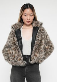 Faux fur wikkeljas met een luipaardpatroon, voorzien van een zwarte leren voorkant, een brede capuchon en een zachte textuur.