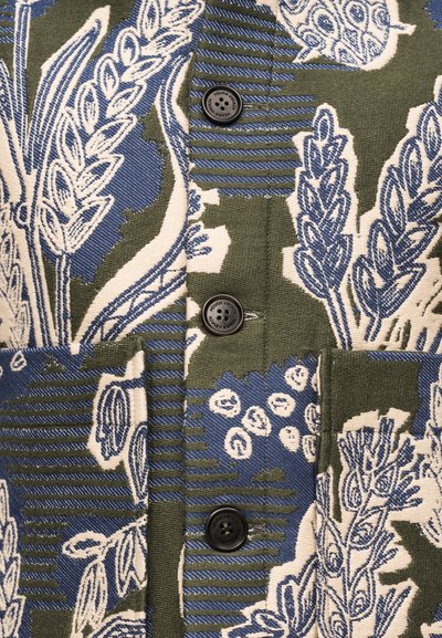 Πράσινο και μπλε ύφασμα με σχέδια σιταριού, με τρία μαύρα κουμπιά με ετικέτα "Henrik Vibskov."