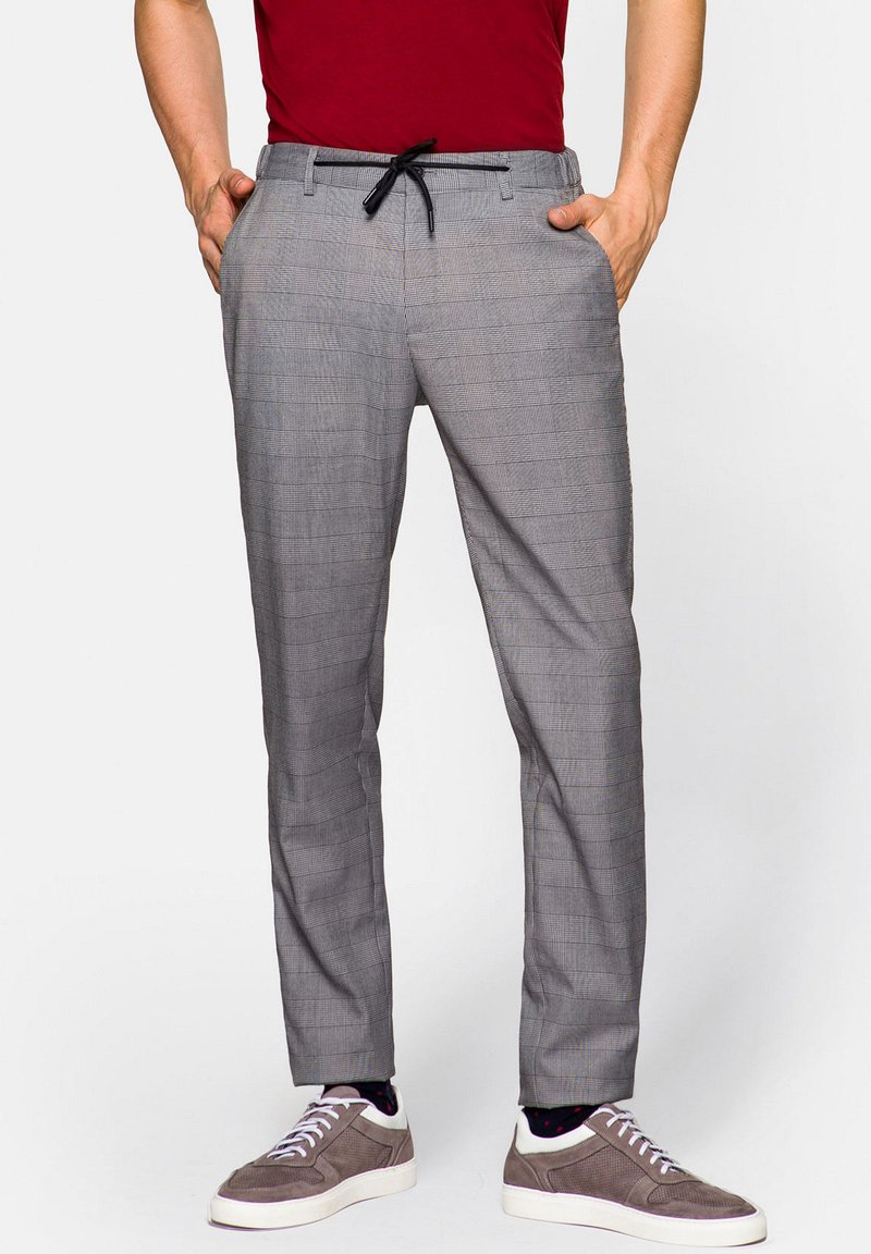 Szare spodni w kratę z elastycznym paskiem, o dopasowanym kroju i gładkiej fakturze, zestawione z szarymi trampkami.